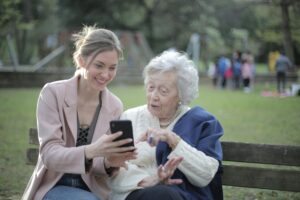 A younger woman shows an elderly woman somehting on her phone